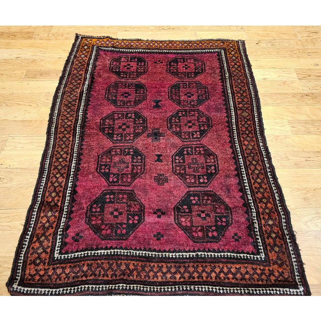 This vintage Afghan Bokhara area rug, hand-knotted in the mid-20th century, features the signature allover geometric gul...