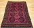 This vintage Afghan Bokhara area rug, hand-knotted in the mid-20th century, features the signature allover geometric gul...