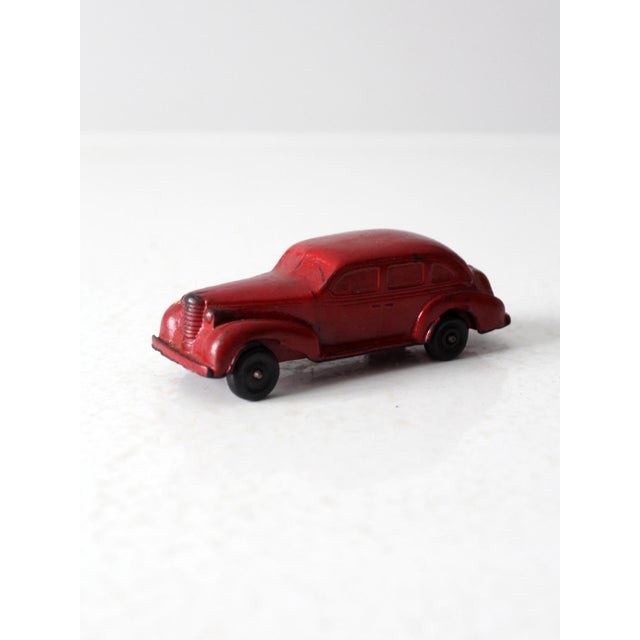 This late 1930s Auburn Rubber Co. toy car, reminiscent of a 1937 Oldsmobile, features a sleek streamlined design in red...