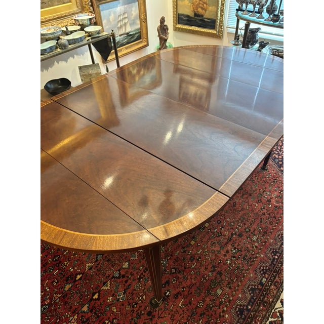 This versatile banded drop leaf mahogany dining table was produced by Baker Furniture Company. It was purchased at Gump's...