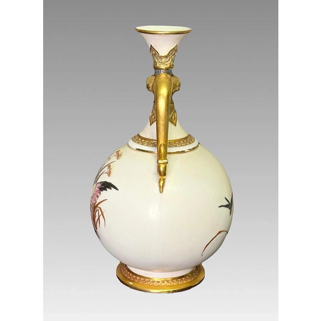 Elegant ivory toned, mat glazed Royal Worcester vase with twin 24 carat gilded stylized dolphin form handles. Depicts pink...