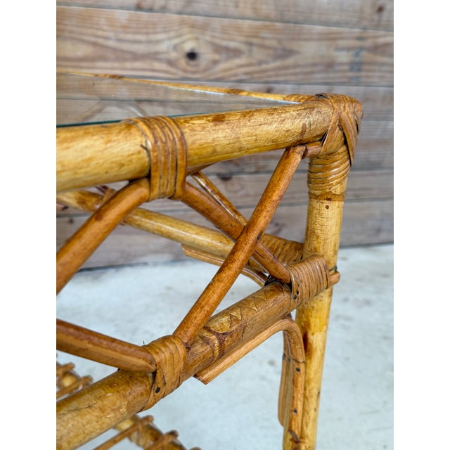 Charming vintage rattan and bamboo coffee table featuring a beautifully woven frame with decorative wrapped joints and a...