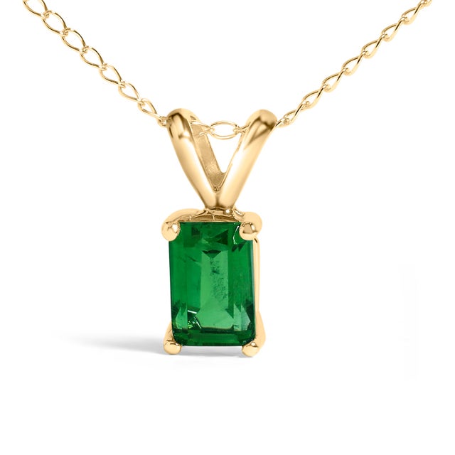 Draped in the regal splendor of a color-enhanced, natural emerald, this 14K yellow gold pendant necklace exudes elegance...
