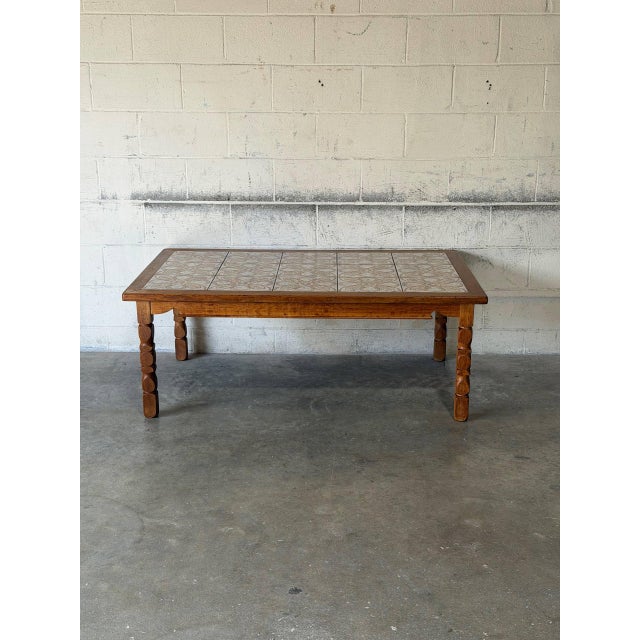 This striking coffee table features an inset ceramic tile top with intricate floral patterns and sturdy turned legs....