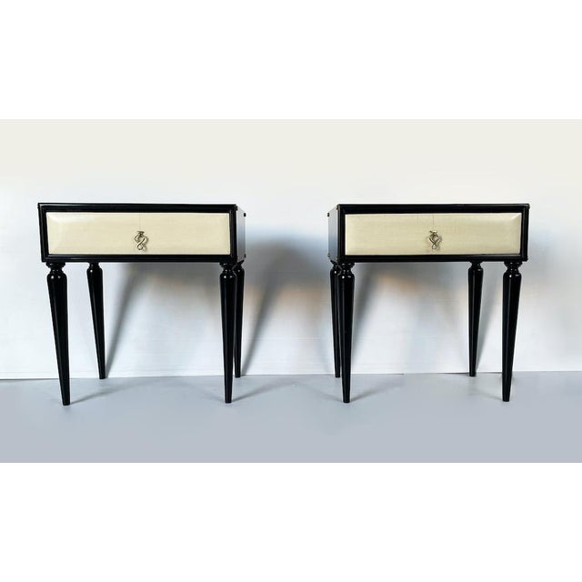 A unique pair of fully restored 1950s bedside tables. Each is made of black lacquered wood and features a parchment-lined...