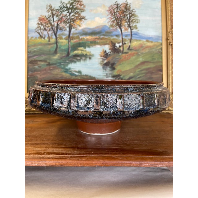 A striking mid-century modern studio pottery bowl featuring a wide, shallow form elevated on a cylindrical foot. The...