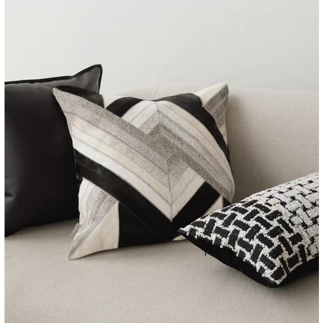 This genuine cowhide throw pillow features abstract geometric cutting, with black, white, and gray colors colliding to...