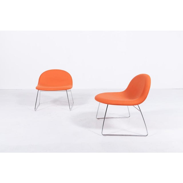 3D designed by Komplot Design for Gubi is a chair with shell in HiRek upholstered in red orange fabric and sledge steel...