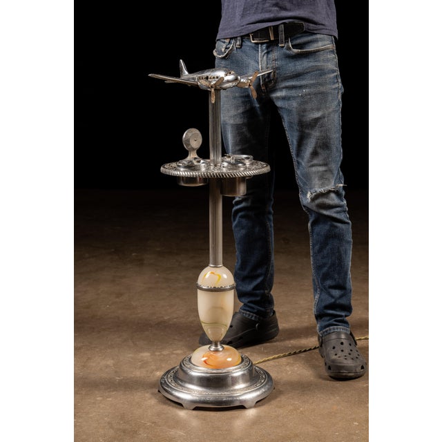 Chrome-plated smoking stand combining aviation-themed design with multiple smoking accessories and integrated lighting....