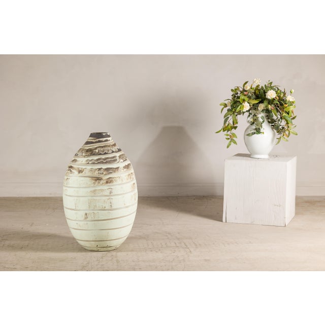 This large artisan ceramic vase features a softly rounded, elongated ovoid silhouette rising to a gently tapered neck. Its...
