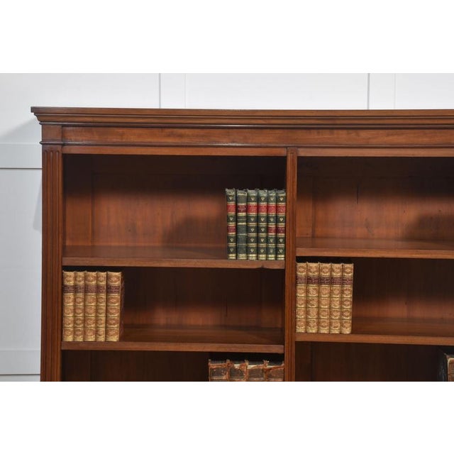 Mahogany open bookcase, the large rectangular well-figured top. Above two bays of adjustable shelves, divided by columns....