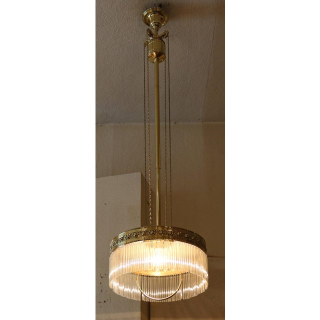 Art Nouveau chandelier, made 1915/20. Brass shade with raised rose decoration all around. Height adjustable via brass pull...