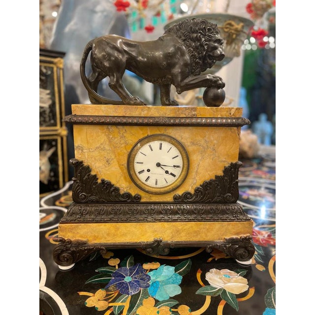 An exquisite early 19th-century French clock featuring a finely cast bronze lion resting majestically atop a beautifully...