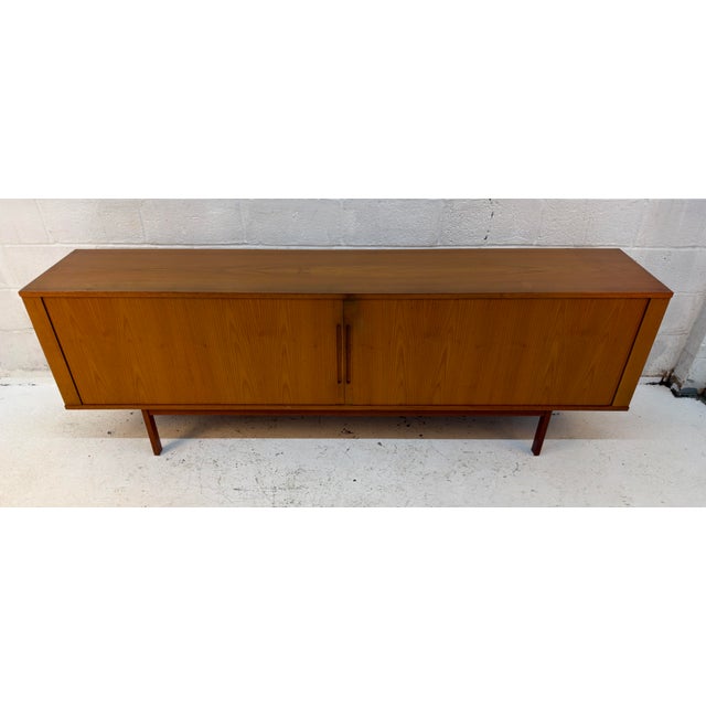Beautiful Mid-Century Modern teak credenza featuring distinctive tambour doors that slide smoothly to reveal generous...