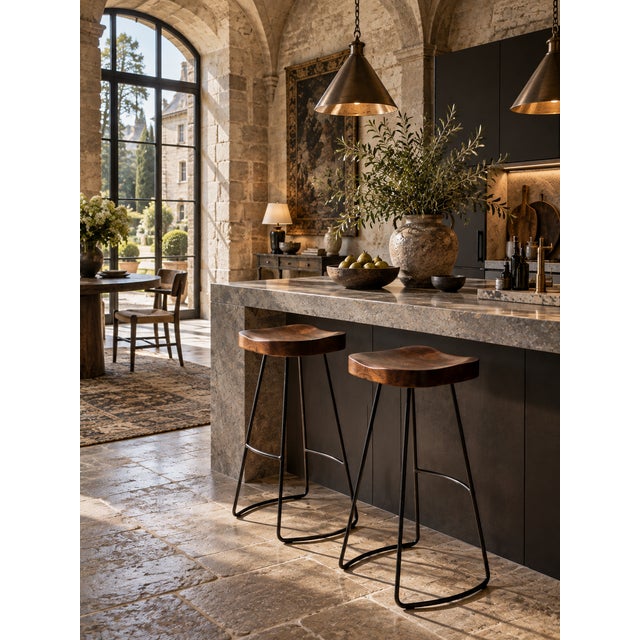 A pair of vintage bar stools pairing richly grained sculpted wood saddle seats with slender black iron rod frames. The...
