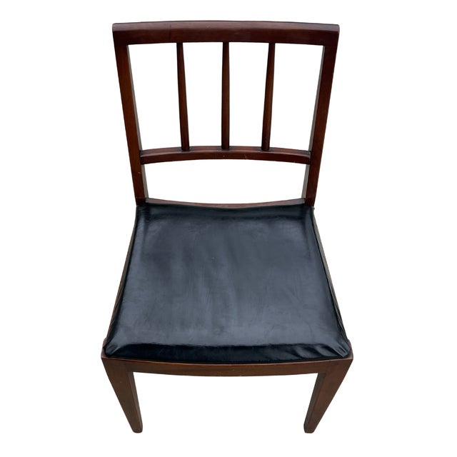 Handsome vintage wood side chair featuring a warm, dark-stained frame and a sleek black upholstered seat. The chair has a...