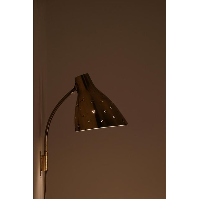 This perforated brass wall lamp model 50-055 designed by the renowned Finnish designer Lisa Johansson-Pape. with its...
