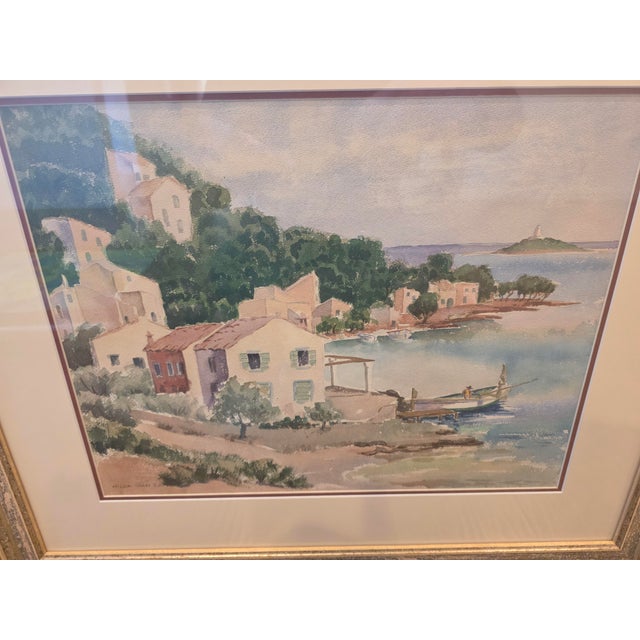 This original watercolor depicts a charming coastal village overlooking a tranquil harbor. The composition features softly...