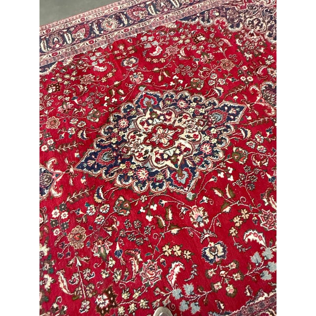 Design Plus Gallery presents a 9ft 6in × 12ft 6in Persian Wool Area Rug. The rug displays a red field with an intricate...