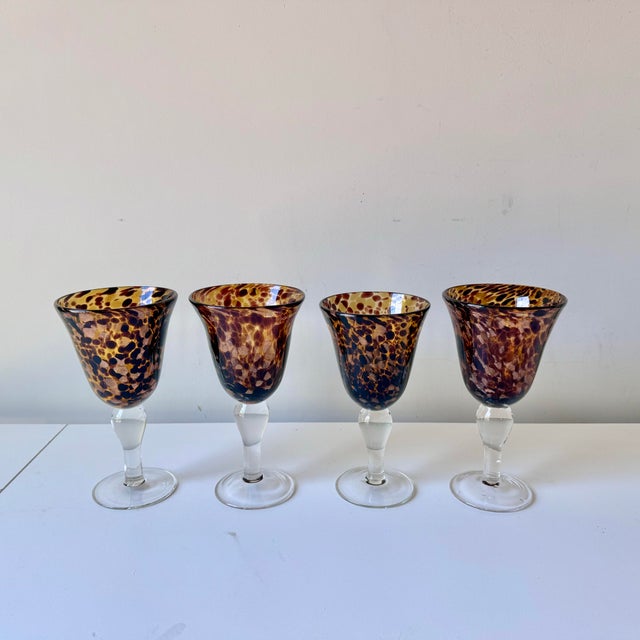 Vintage set of four blown tortoiseshell glass wine goblets with clear stems. The set has a bit of sparkle with copper...