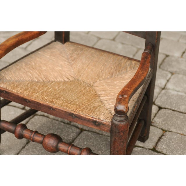 An English William and Mary style oak youth chair from the late 18th century, with rush seat and spindle back. This...