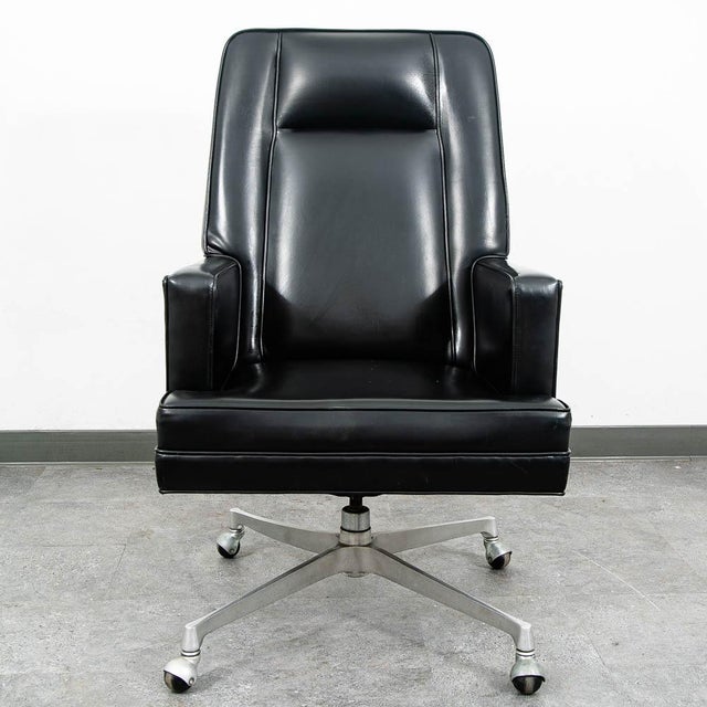 Vintage black vinyl executive chair. Sits on a metal rolling base. Unmarked example.