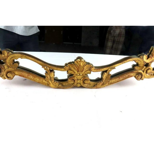 A richly carved 19th-century Louis XV style giltwood mirror, the scrolling asymmetric crest composed of rocaille, foliate...