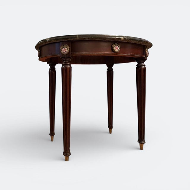 Circular bouillotte table executed in the louis xvi style. the table features a round marble top set within a mahogany...