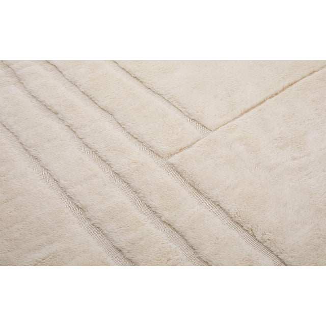 Contemporary hand-knotted wool rug in Pearled Ivory, featuring an abstract linear pattern with intersecting lines and soft...