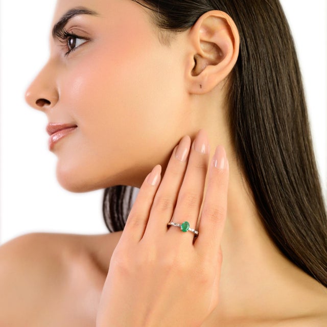 This delicate minimalist ring showcases a beautiful 0.55 carat oval emerald measuring 7×5 mm, highlighted by subtle 0.06...