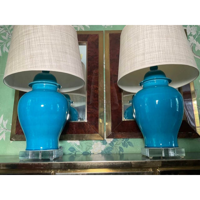Large, urn shaped, bright turquoise table lamps raised on a circular lucite bases, each with 1-light and natural woven...
