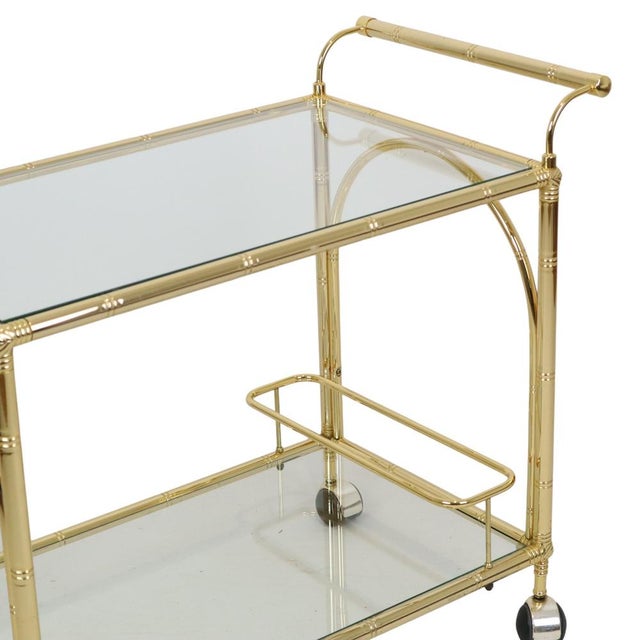 A stunning vintage trolley/bar cart made of gold-tone chrome-plated metal with glass shelves; a quintessential Hollywood...