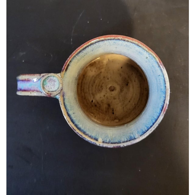 This is a vintage studio pottery mug. The hand-crafted ceramic mug has a striking blue and purle glaze. Base is signed by...