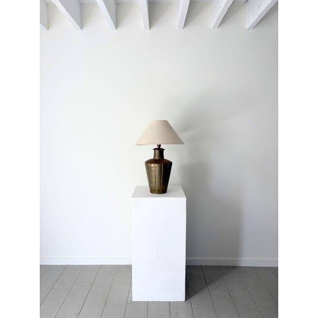 A charming Indian brass lamp with distinct vertical fluted panels tapering toward a narrow circular base. The aged metal...