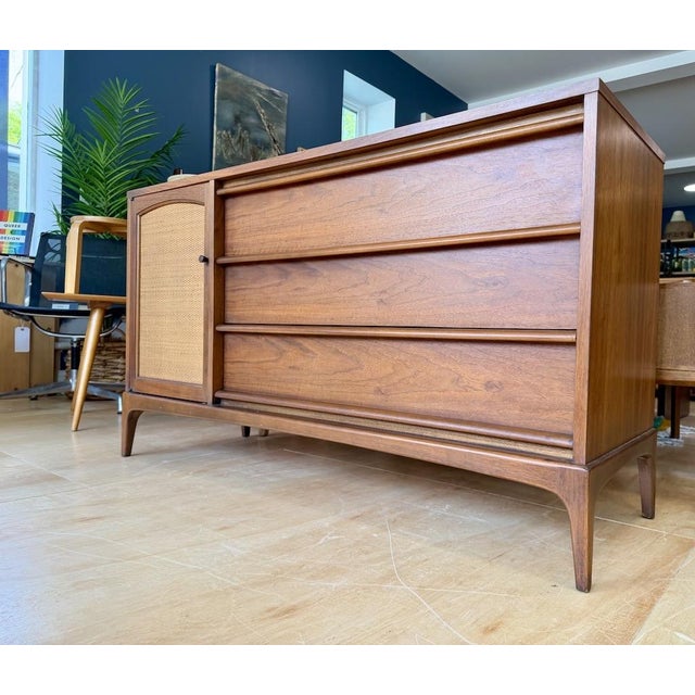 Mid Century Lane Rhythm Walnut Credenza that features a reversible front panel with woven cane on one side and finished...