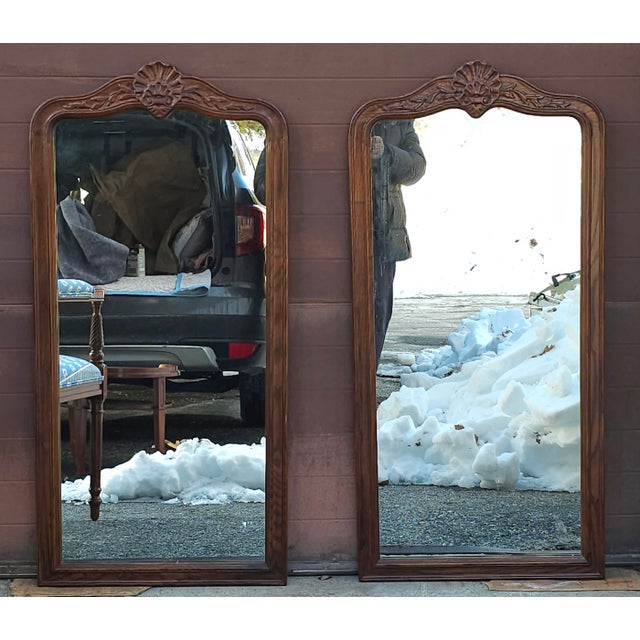 A Pair of Mid Century Carved and Stained Oak Framed Wall Mirrors. Measures 22.5" in width, 46.75" in height and 1.5" in...