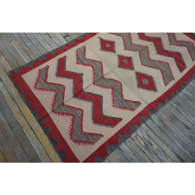 A study in cream and earthy brown tones, the field floats three fringed central lozenges and six broad, plain zigzags,...