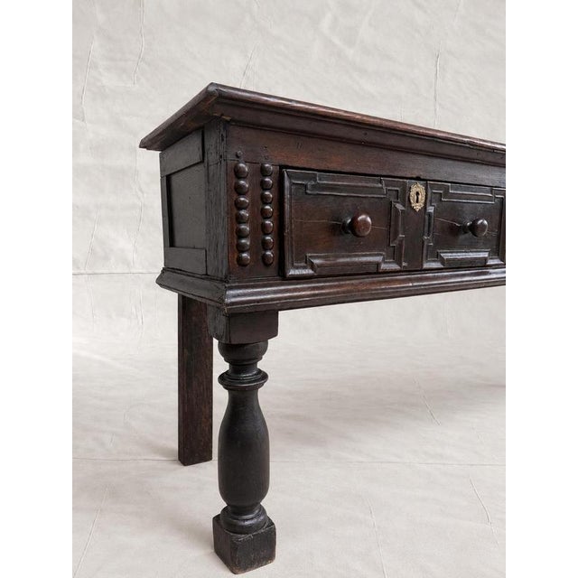 A late 17th-century solid English oak console, circa 1680, with a rich dark brown patina. The long, shallow form has a...