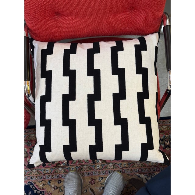 Geometric design pillow in black and white. The body is white and has raised black geometric designs and a solid black...