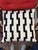 Geometric design pillow in black and white. The body is white and has raised black geometric designs and a solid black...