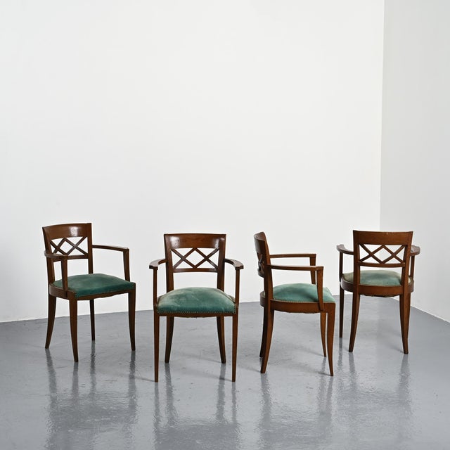 Set of four French armchairs made around 1940. The dark-stained solid oak frame features gently curved armrests and a...