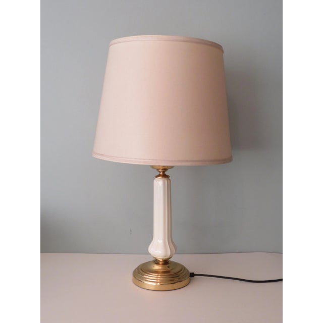 Impressive lamp with white ceramic and brass base and fixture. The lamp has an cream shade, 1 E 27 fitting and a on and...
