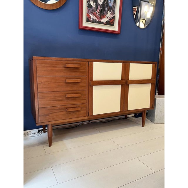 Teak sideboard with ivory vinyl-covered doors. Typical Italian light-colored interior and glass shelf. Four drawers.