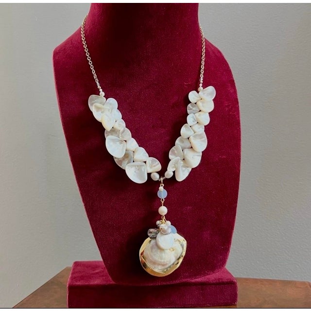 A stunning piece that combines a natural seashell pendant, lined in gold with luxurious faceted aquamarine beads, Mother...