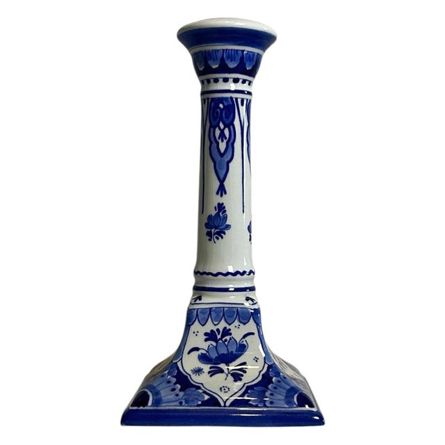 A hand-painted royal delft candlestick by de porceleyne fles, made in 1973. The piece has a square base, a tall...