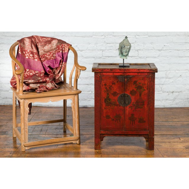 A Chinese Qing Dynasty period red lacquered small cabinet from the 19th century, with painted flowers and vase scene....