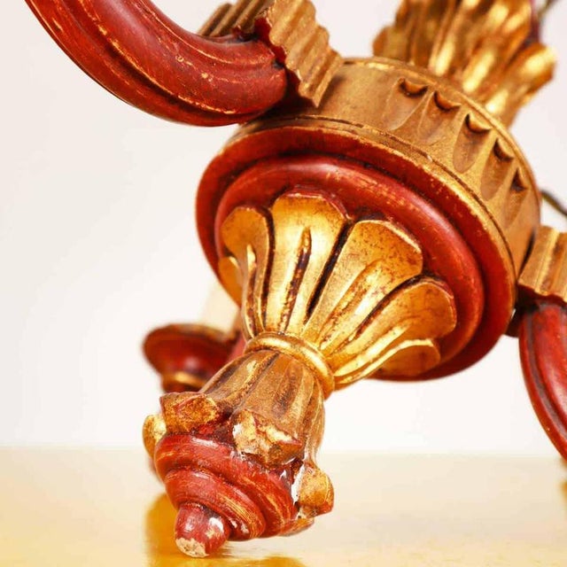 Elegant wooden chandelier, featuring gold finishes and an eye-catching red color. This vintage chandelier features a...