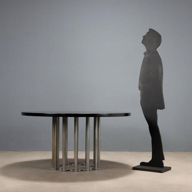 Vintage dining table with round top in black lacquered wood, chromed metal leg. This piece is attributed to the mentioned...