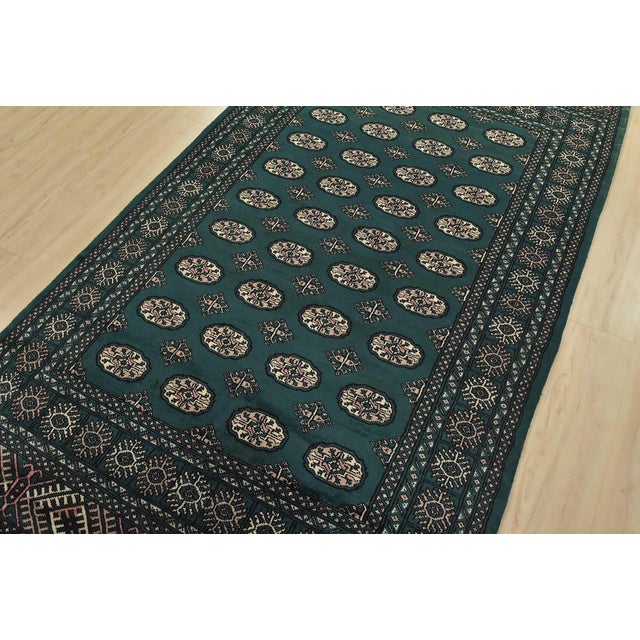 A tribal Bokhara rug hand-knotted with an all-wool pile on a cotton foundation. This finely woven oriental rug features...