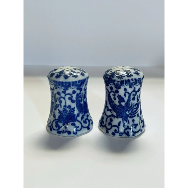 A set of Japanese salt & pepper shakers featuring a phoenix with outspread wings surrounded by a scrollwork pattern of...